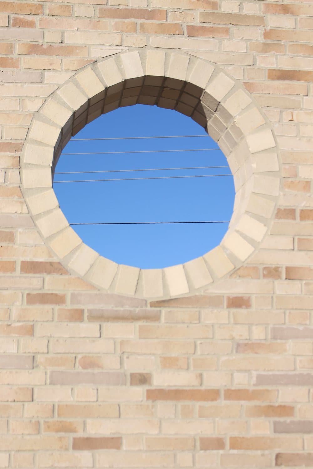 Circular window opening in cream brick facade