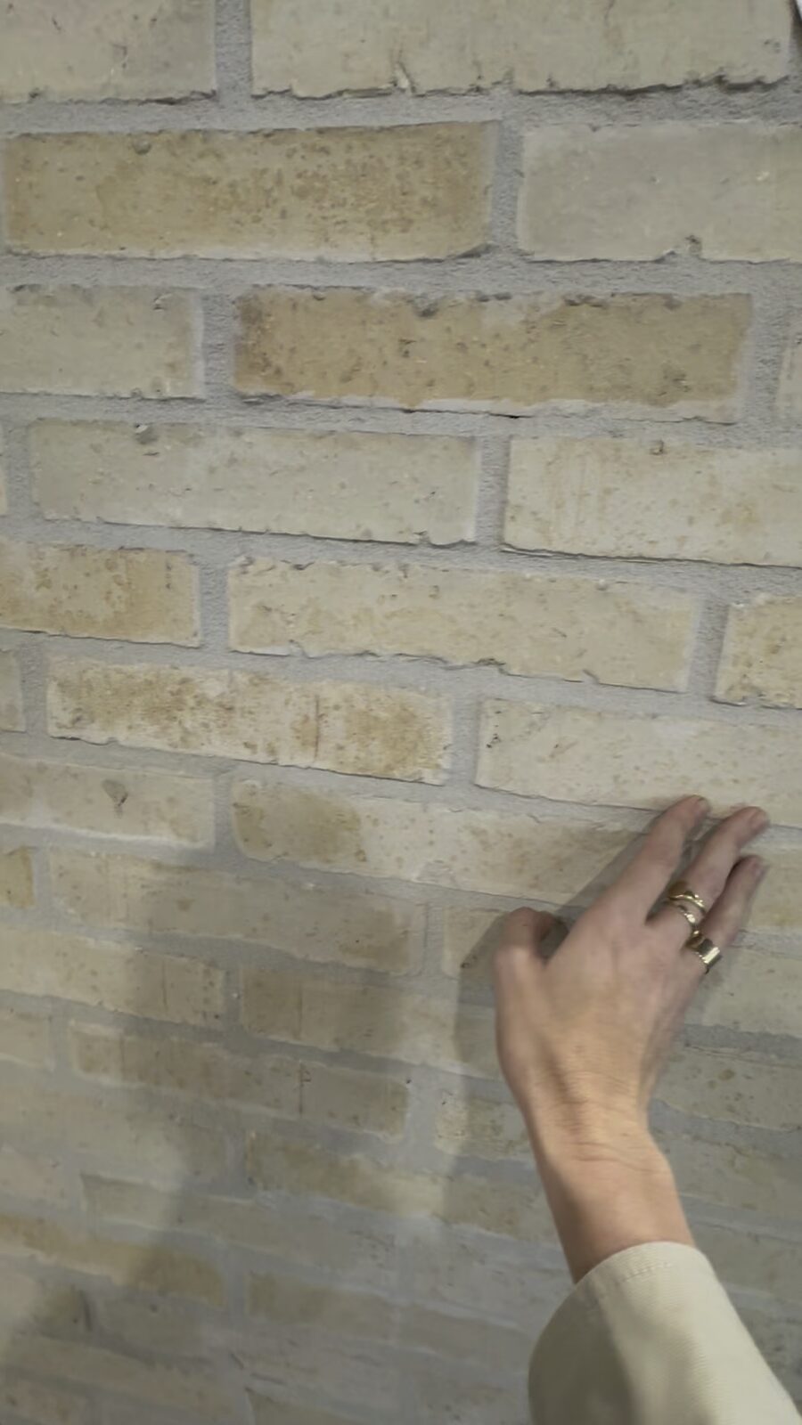 Close-up of a hand touching a cream Nexbrick brick-slip facade panel on the Krause Bricks stand at Futurebuild 2026.
